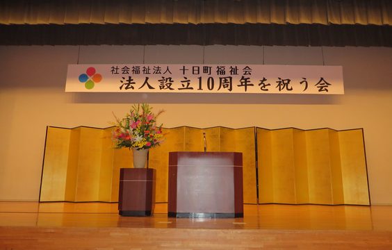 「法人設立10周年を祝う会」の横断幕が掲げられた式典会場