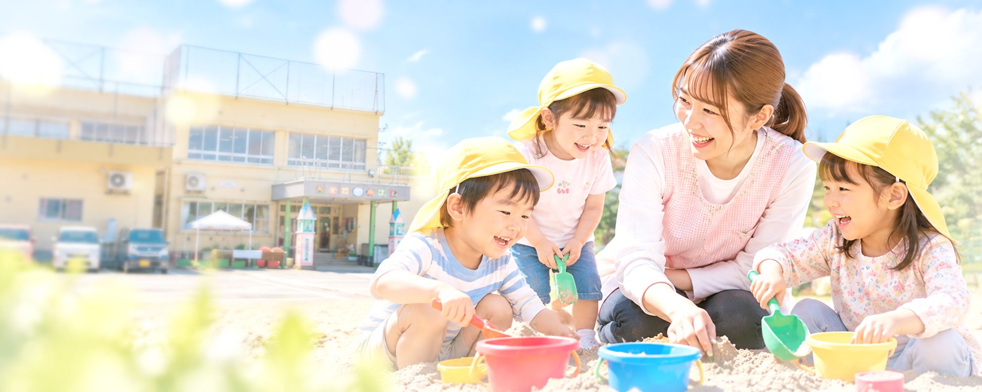 しんざこども園の園庭の砂場で遊ぶ子どもたちと保育士